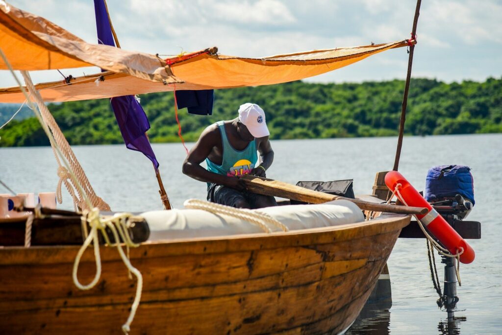A man works on a boat at the water's edge
